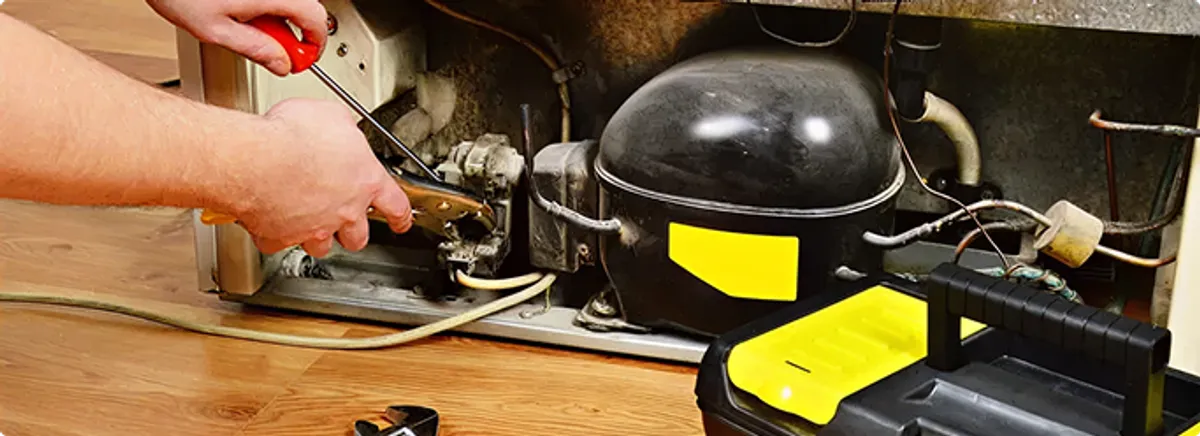 Refrigerator repair technician fixing the compressor and wiring in Yukon, OK