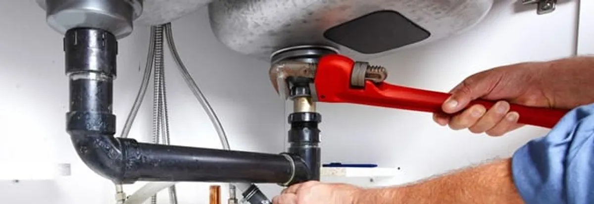 Garbage disposal repair technician tightening the sink drain and disposal connection in Oklahoma City, OK