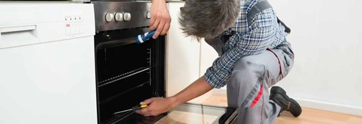 Oven repair technician inspecting and servicing an electric oven in Oklahoma City, OK