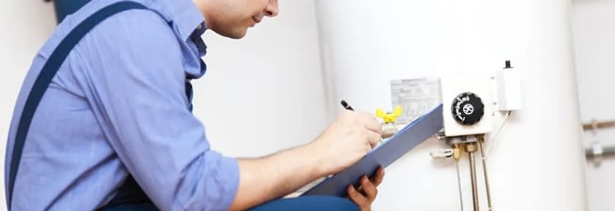 Water heater repair technician inspecting the unit and recording service notes in Oklahoma City, OK